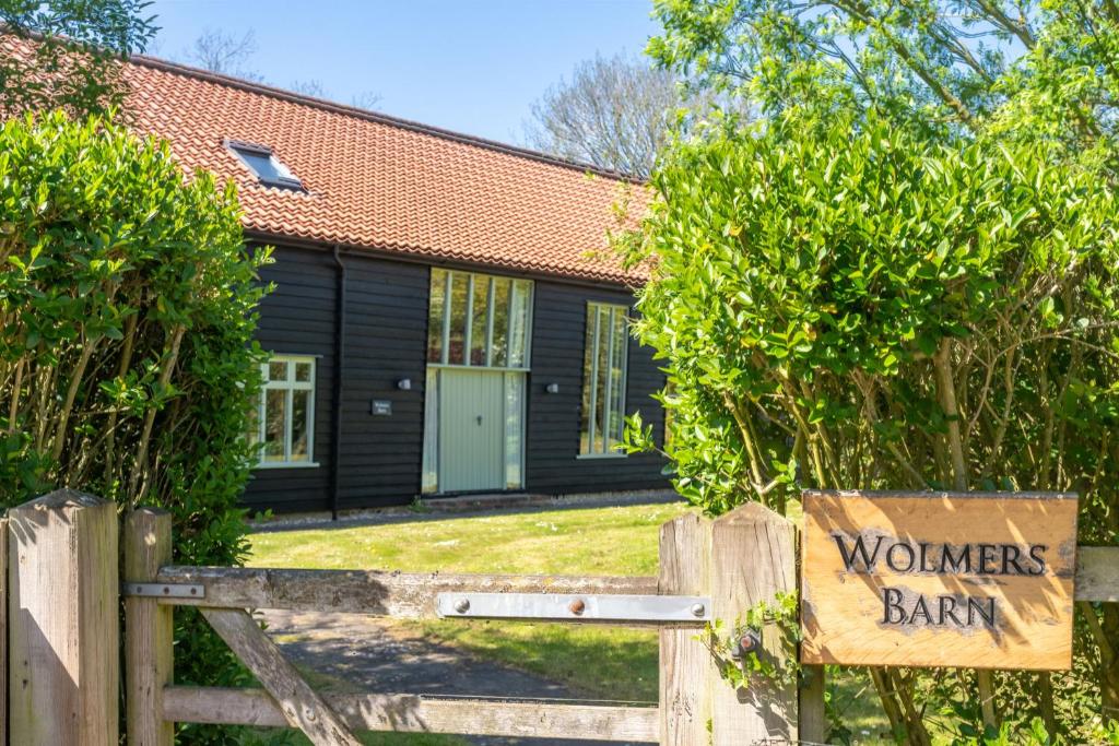 a house with a wooden fence and a sign that says wondersbank at Wolmers Barn in Stonham Aspall