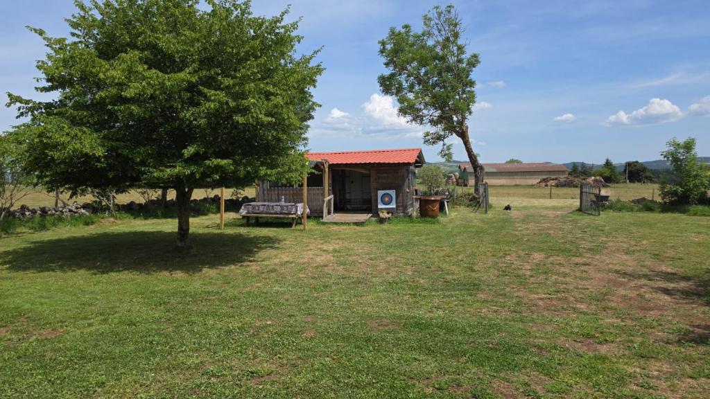 a small cabin in a field with a tree at Le Dômes du Ceyssoux in Le Brignon