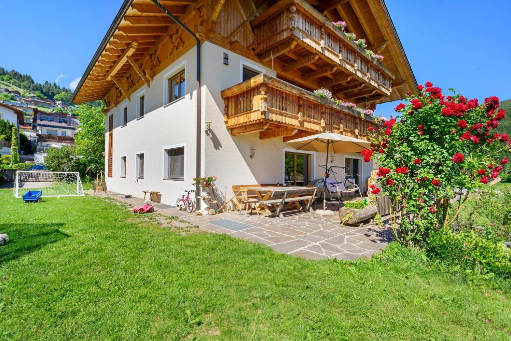 a house with a wooden roof and a yard at Schwabl Auf Der Ebene in Meltina