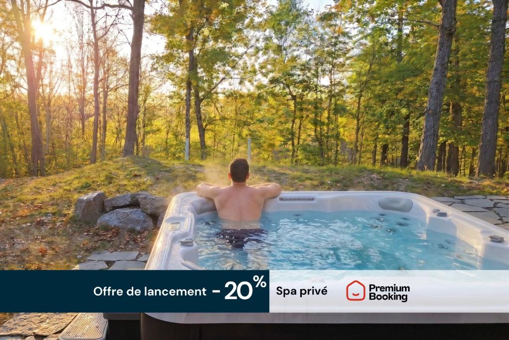 Ein Mann sitzt in einem Whirlpool im Wald. in der Unterkunft Elios Private Spa & BBQ, Lake & Golf in Brownsburg