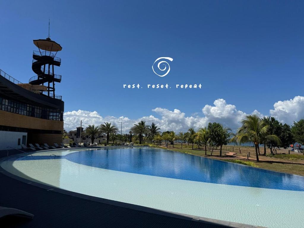 a large swimming pool in front of a building at J-Stays 2BR Beach Condo at Seafront Residences in San Juan