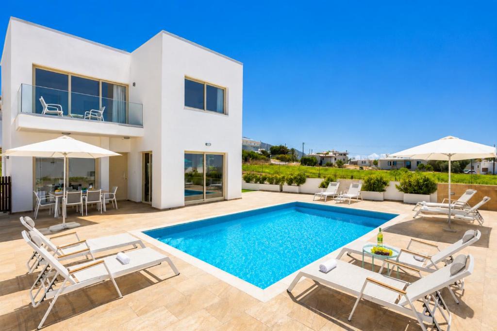 a villa with a swimming pool and patio furniture at Villa Diana Seaside in Pomos