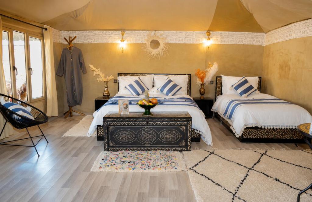 a bedroom with two beds with blue and white pillows at Aladdin merzouga camp in Merzouga