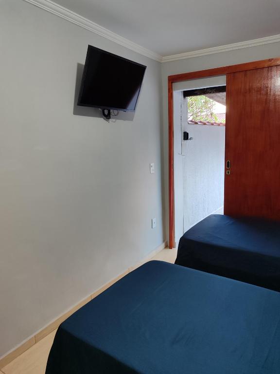 a bedroom with two beds and a tv on the wall at kitnet individual Campinas in Campinas