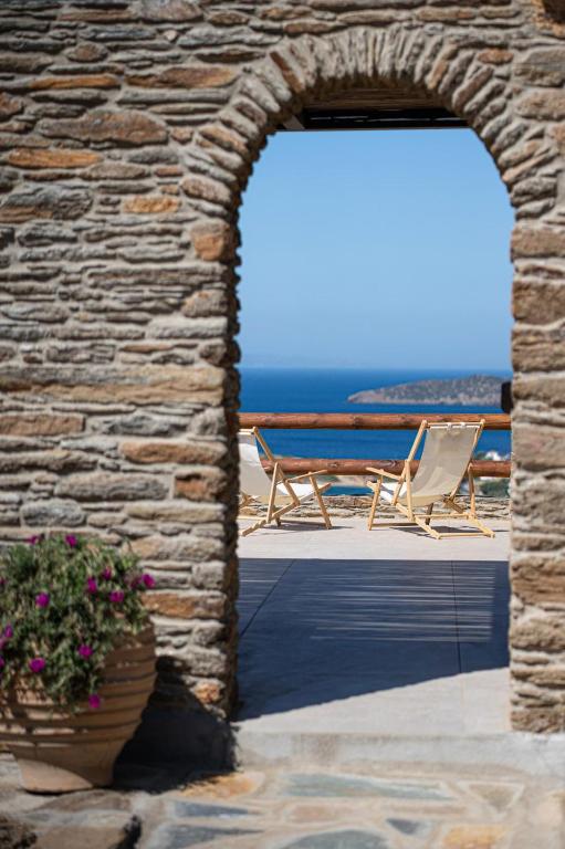 a stone wall with two chairs and a table and a patio at Lithoskino Suites in Batsi
