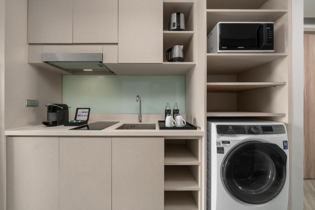 A compact kitchenette with a sink, microwave, coffee setup and washing machine.