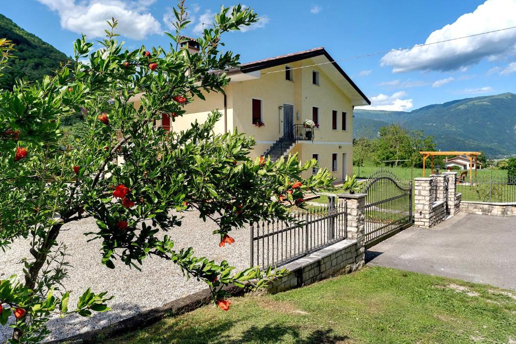 a house with an orange tree in front of a fence at Casa Aria Pura in Alano di Piave