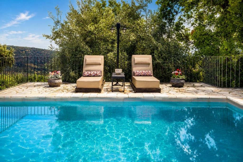 two chairs sitting next to a swimming pool at Blue Jasmine Villa - Private Pool and Garden in Aigio
