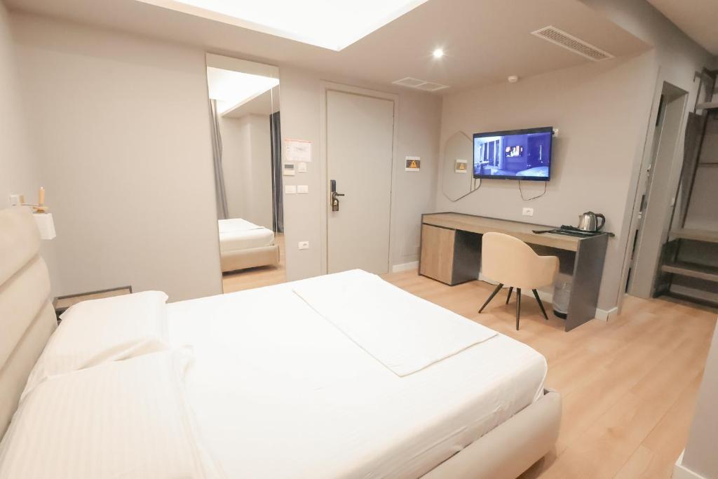 a bedroom with a bed and a desk and a tv at The Real Sea View Hotel Vlore in Vlorë