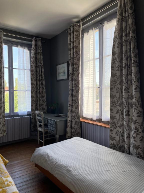 a bedroom with a bed and a desk and windows at Chambre d'Hôte des Arcs in Coulonces