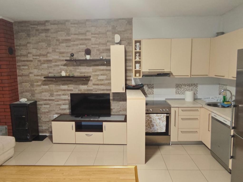 a kitchen with white cabinets and a brick wall at Apartman Daniela in Neum