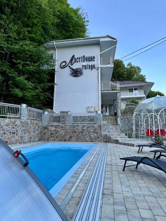 a house with a swimming pool in front of a building at Ластівчине гніздо in Shaian