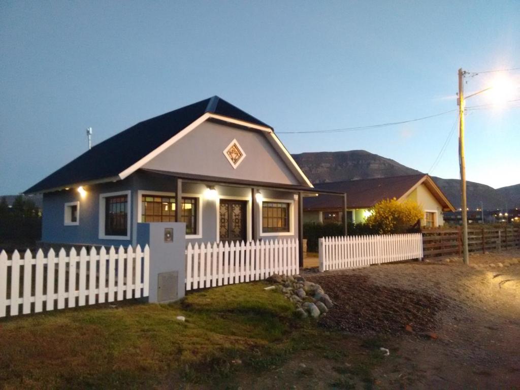 una pequeña casa con una valla blanca en El Abrigo en El Calafate