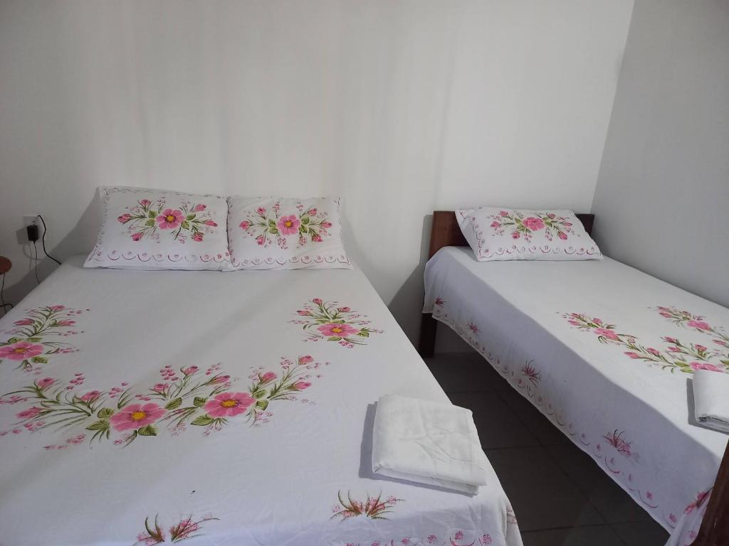two beds in a room with pink flowers on them at Villa Verde Chalés e Restô in Patos