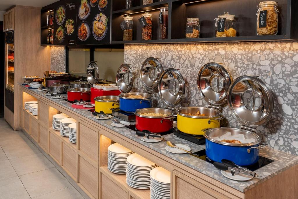 A hot breakfast buffet with covered dishes, plates and shelving of packaged foods.