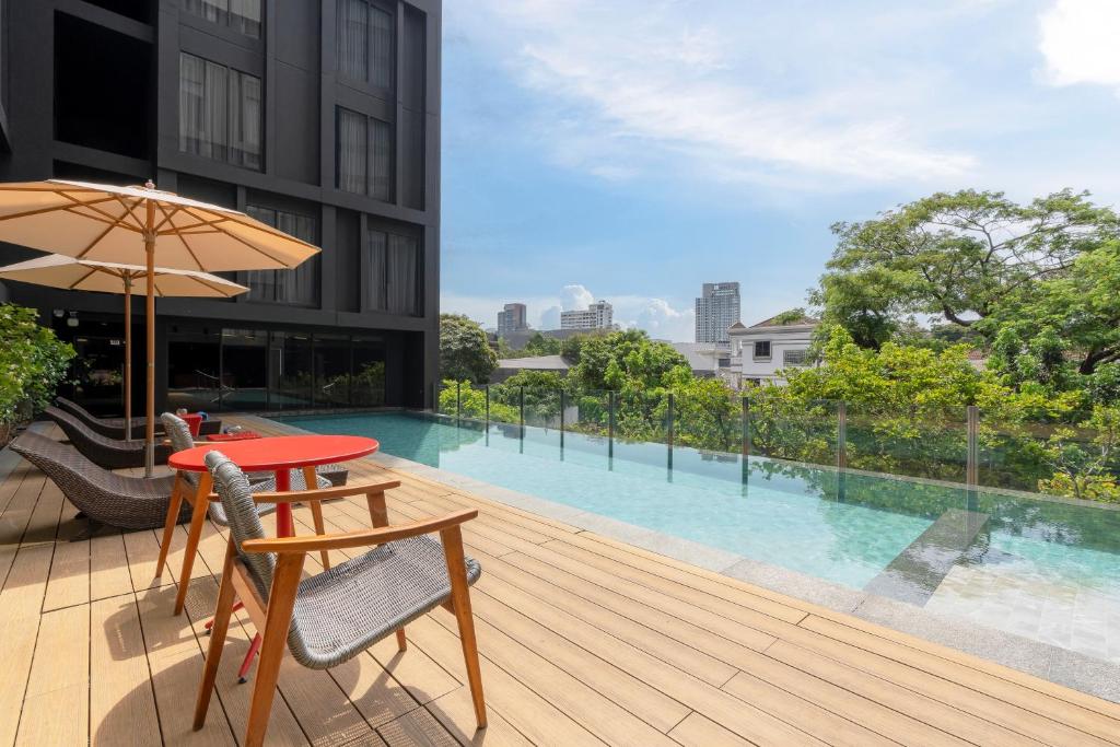 an outdoor deck with a table and chairs and an umbrella at Oakwood Studios Sukhumvit Bangkok in Bangkok