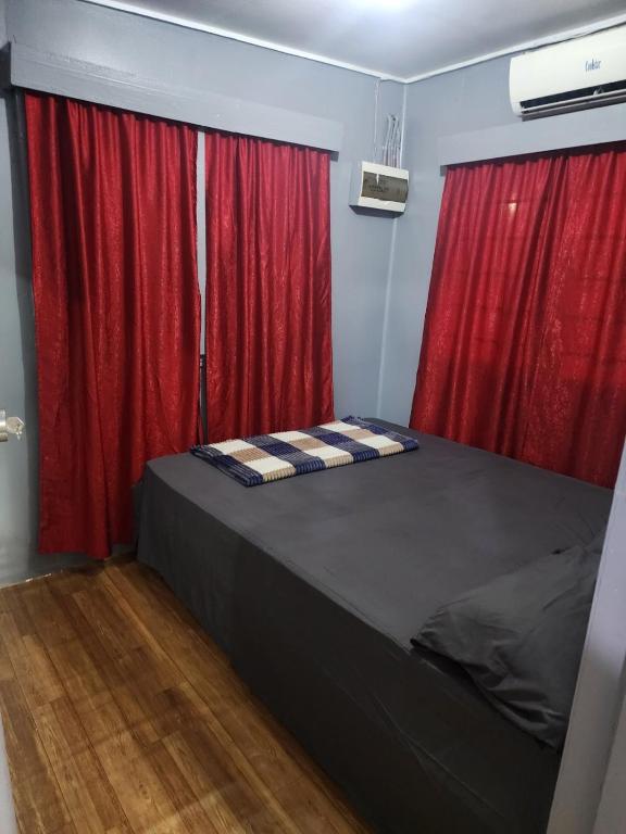 a bedroom with red curtains and a bed in a room at Aaqib Homestay in Suva
