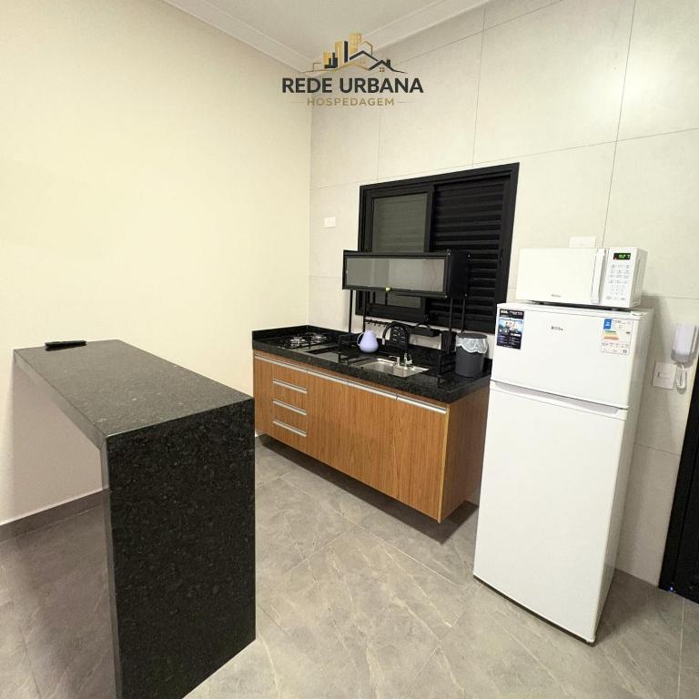 a kitchen with a white refrigerator and a counter at Loft 3 com ar-condicionado da Rede Urbana in Indaiatuba