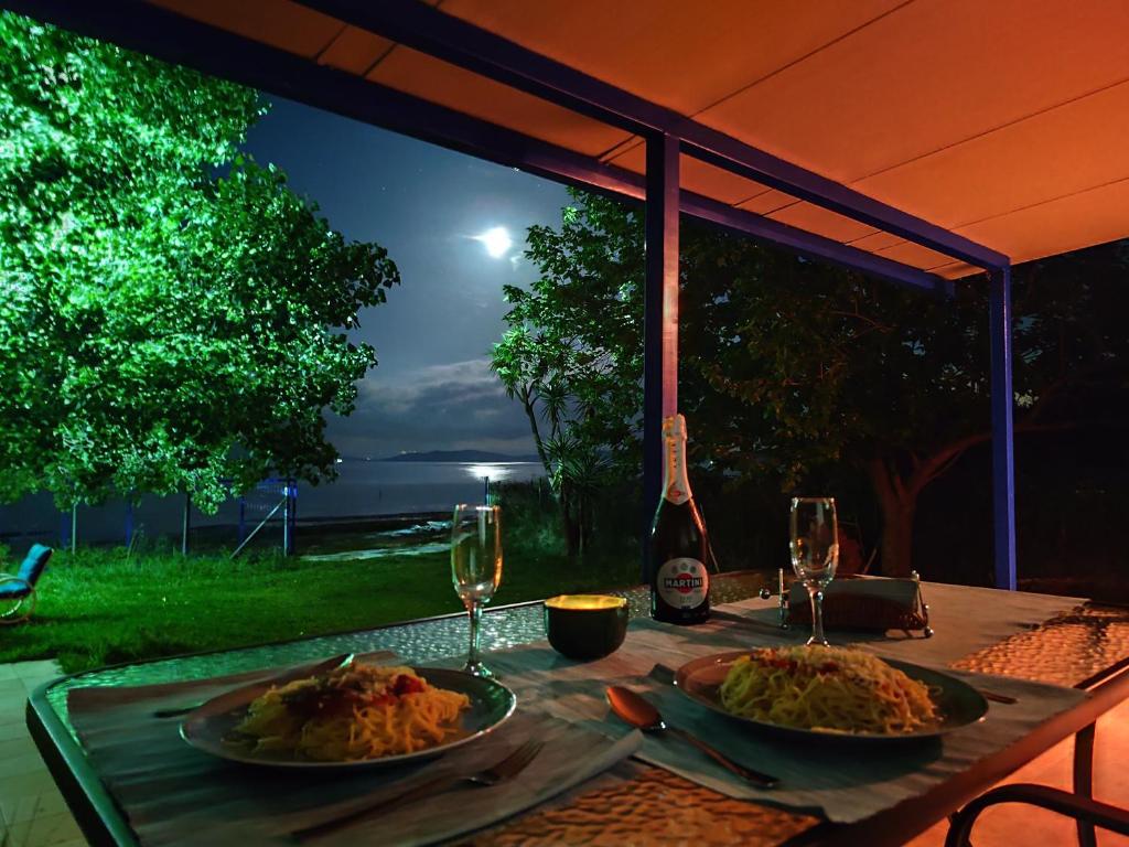 ein Tisch mit zwei Tellern mit Speisen und Weingläsern in der Unterkunft Aviator's Seafront Escape in Ágios Nikólaos