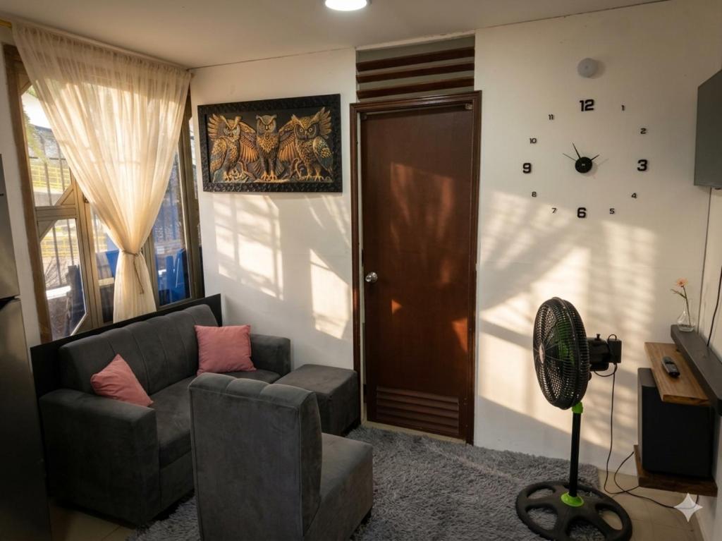 a living room with a couch and a clock on the wall at Apartaestudio amoblado Aeropuerto PIMSA bombona in Malambo