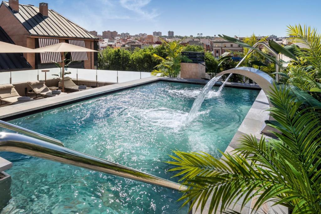 a swimming pool with a water fountain on top of a house at Catalonia El Retiro in Madrid
