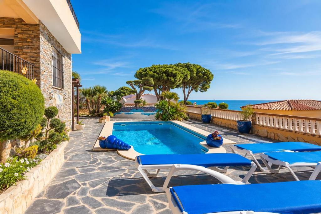 a swimming pool with blue lounge chairs and the ocean at VILLA MIRAMAR in Peniscola