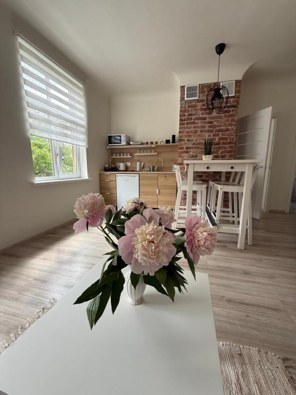 a vase of pink flowers sitting on a table in a living room at Parka ielas apartamenti in Limbaži