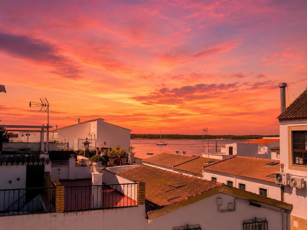 a sunset over the water with buildings and roofs at Casa Cañailla in El Rompido