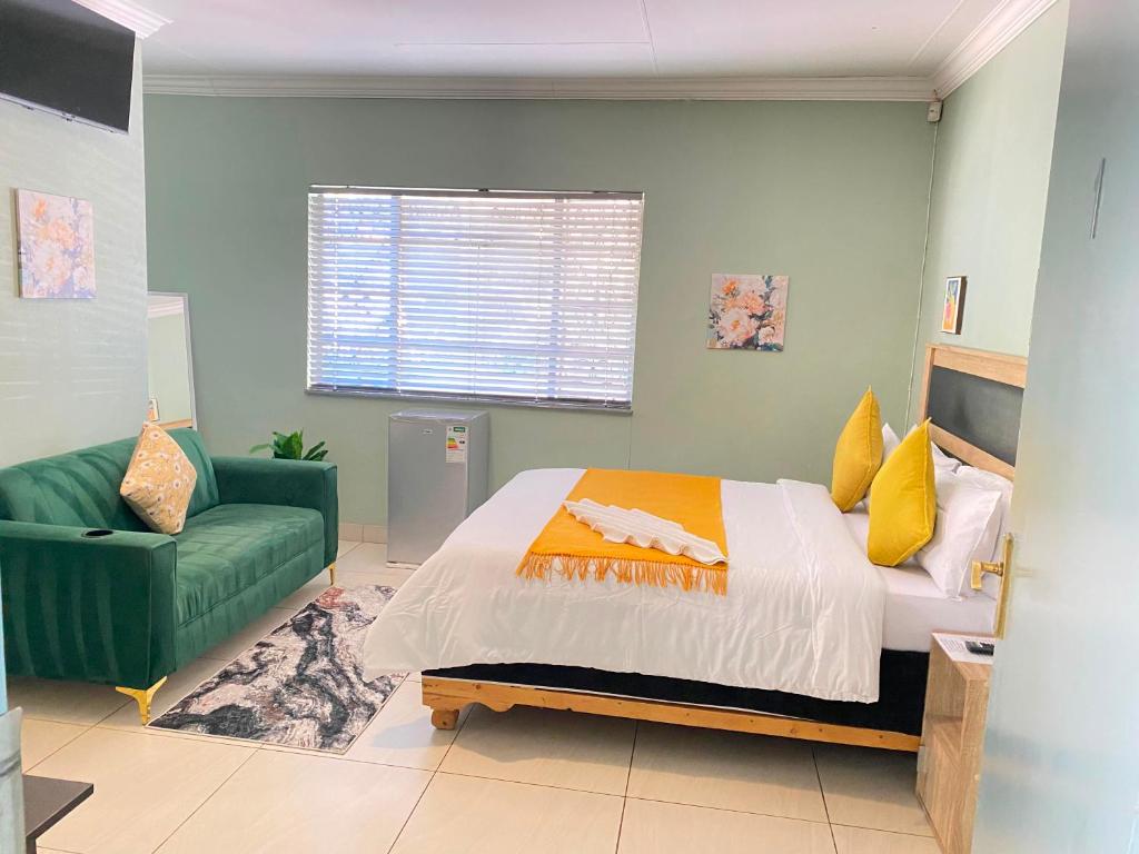 a bedroom with a bed and a green couch at Stay Arcadia Guest House in Pretoria