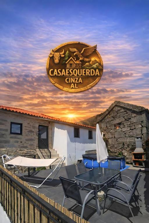 eine Terrasse mit Tisch und Stühlen und einem Schild in der Unterkunft Casaesquerda Cinza in Vieira do Minho