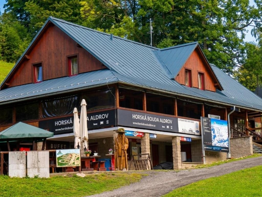 a large wooden building with a black roof at Horská bouda Aldrov in Vítkovice