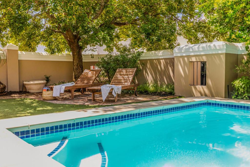 a swimming pool with two chairs and a tree at Mountain views oasis in Franschhoek