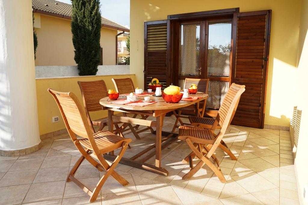 Une table et des chaises en bois sont disponibles sur la terrasse. dans l'établissement Bono Vacanze Casa Bono, à Sciacca