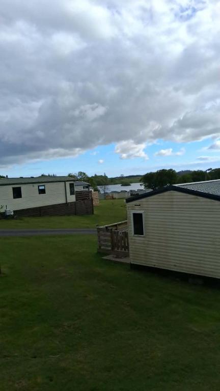 a building with a fence and a grass field at ScotThistle in Kirkcowan