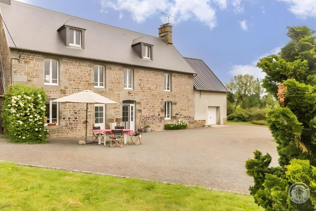 a large brick building with a table and an umbrella at La Bourgerie in Saint-Aubin-des-Bois