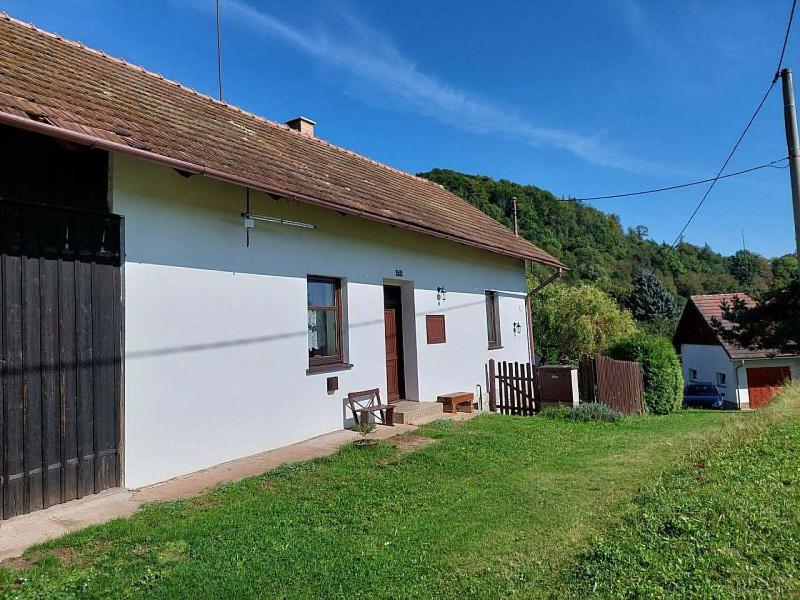 a white house with a bench in front of it at Chalupa na Žampachu in Žampach