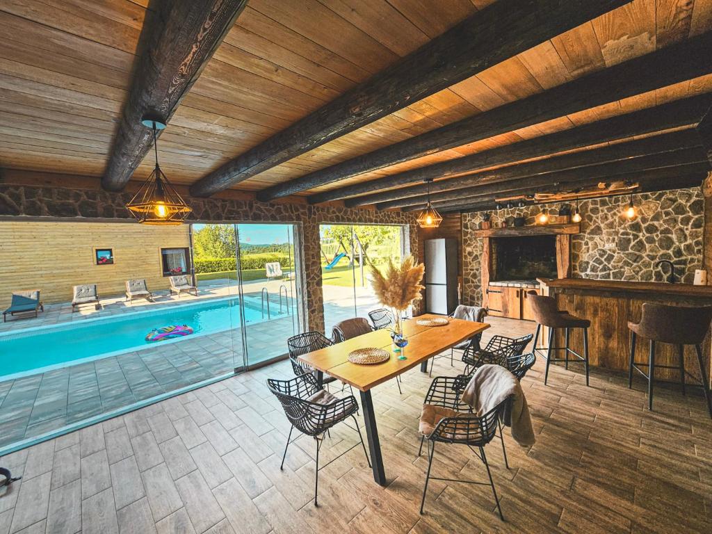 a dining room with a table and a swimming pool at Senjska Villa in Josipdol