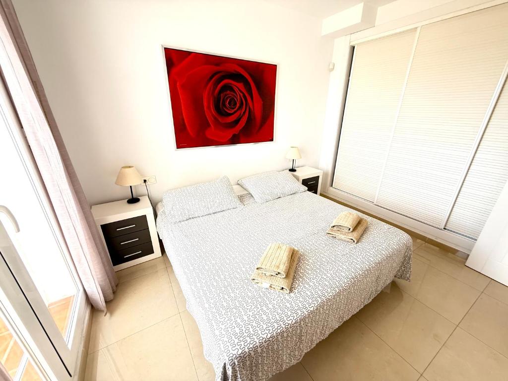 a bedroom with a bed with a red rose on the wall at Heavenly Homes Mojacar 73 in Mojácar