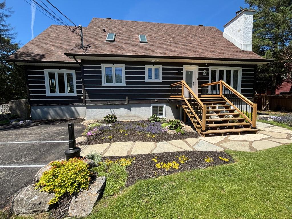 a black house with a porch and a deck at Le Pimbina in Mont-Tremblant