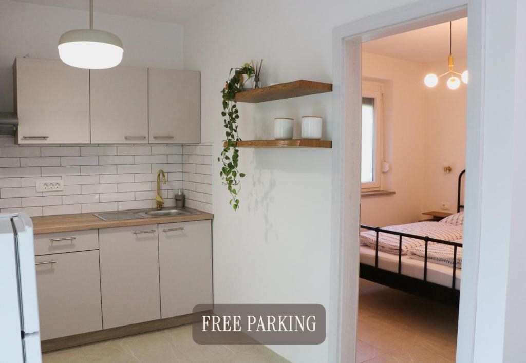 a kitchen with white cabinets and a room with a bed at Between Pines&Sea Strunjan in Strunjan