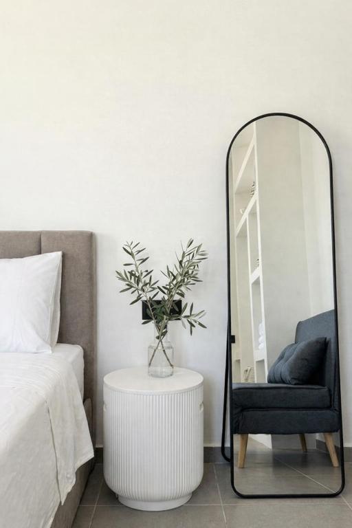a bedroom with a mirror and a chair next to a bed at Ovio II in Kampos Paros