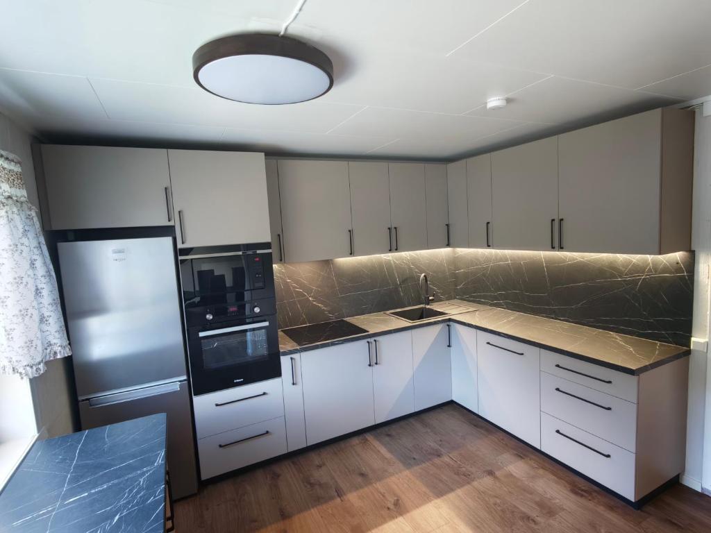 a kitchen with white cabinets and a black appliances at Hus Gryllefjord in Gryllefjord