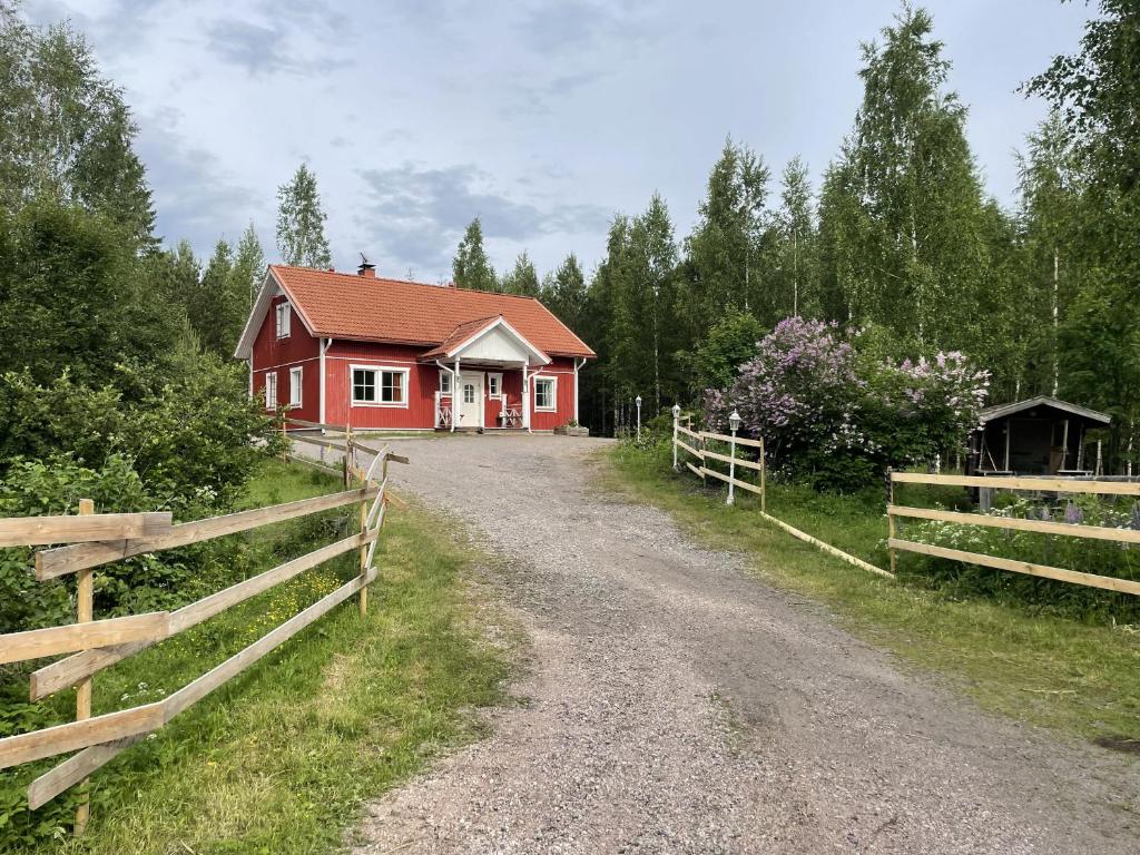 a red house on a dirt road next to a fence at Koivuniemen Ranch in Hämeenlinna