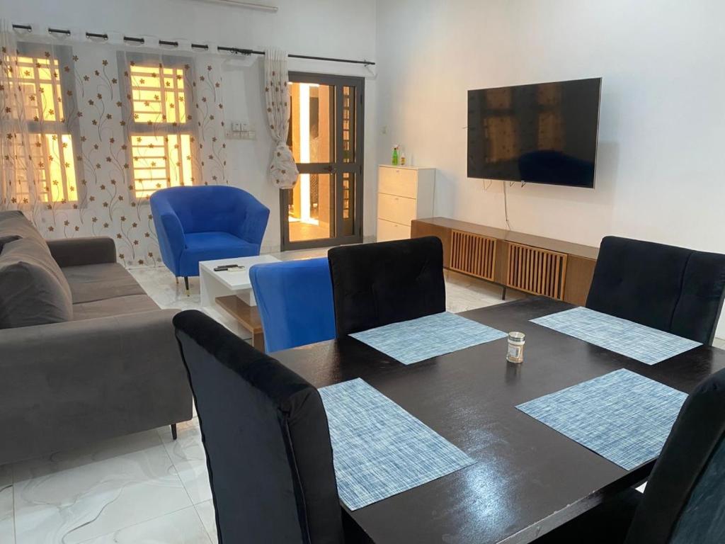 a living room with a table and blue chairs at Central Residence & Conciergerie Ouaga 2000 in Ouagadougou