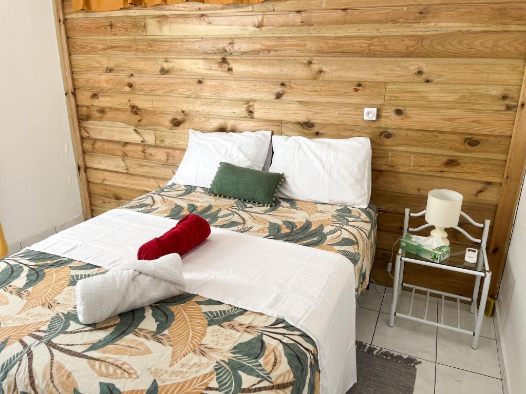 a bedroom with a bed with a wooden wall at Bas de villa 3 chambres - Jardin privé - 20 minutes aéroport in Baie-Mahault