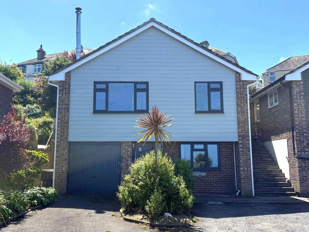 a white house with a garage at Ocean View, 3 bed 2 bath, Dog Friendly, Private parking, Beach 9 min walk, sleeps 6 in Ilfracombe