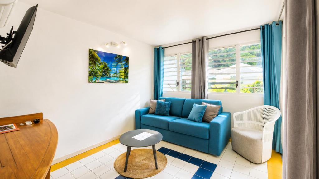 a living room with a blue couch and a chair at L'Ecrin d'Oliv - Jardin, Accès plage, Calme assuré in Grand-Bourg