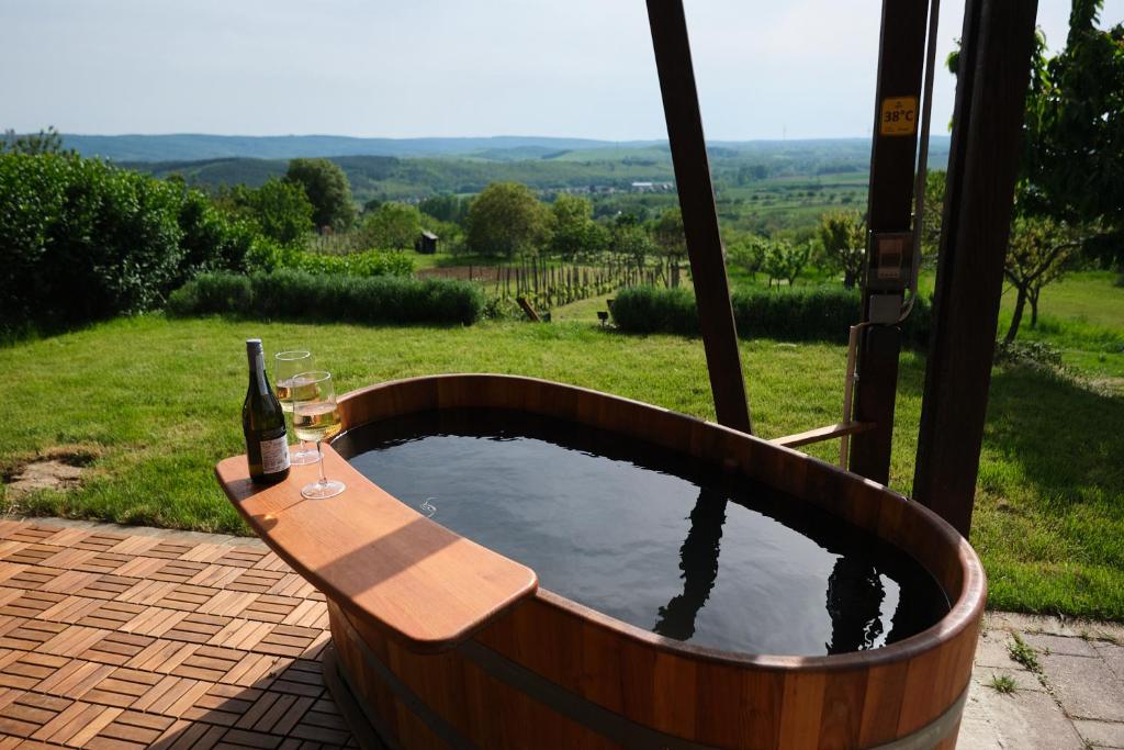 a wooden tub with a bottle and glasses of wine at Pajkos Présház in Bakonycsernye