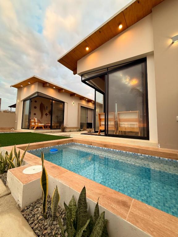 a house with a swimming pool in front of a house at El Rubio Beach Bungalows in Zorritos