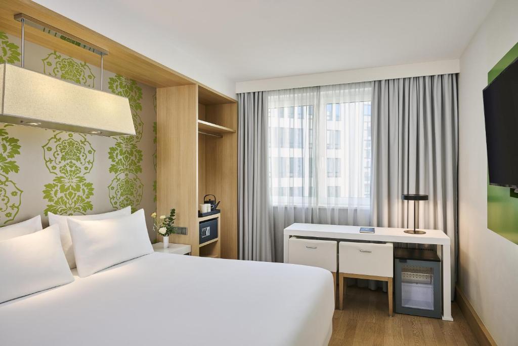 a hotel room with a bed and a desk at NH Berlin Potsdamer Platz in Berlin